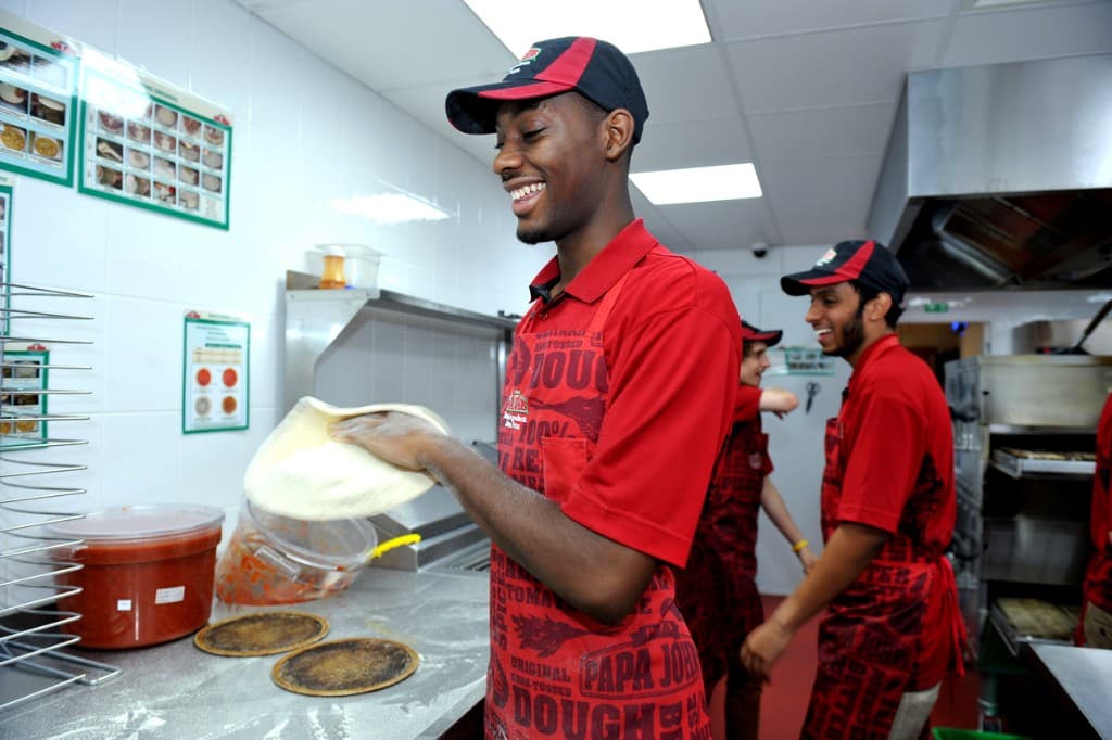 Papa Johns team stretching pizza dough in the kitchen